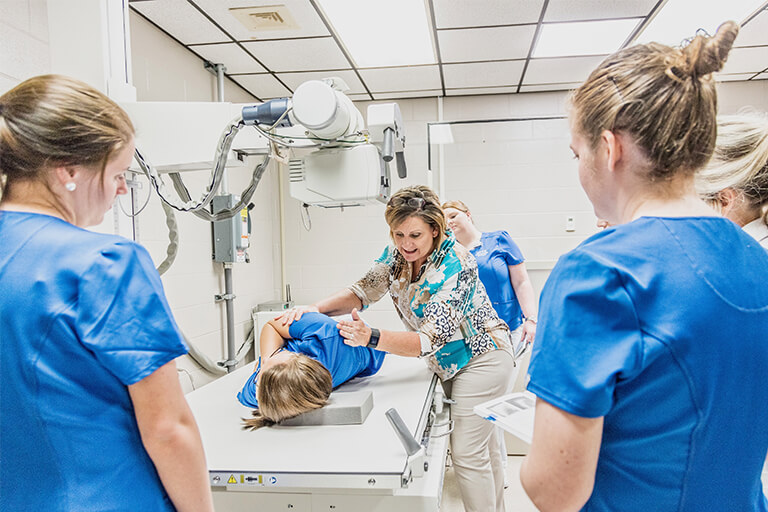 women in nurse scrubs examining someone on an examination table