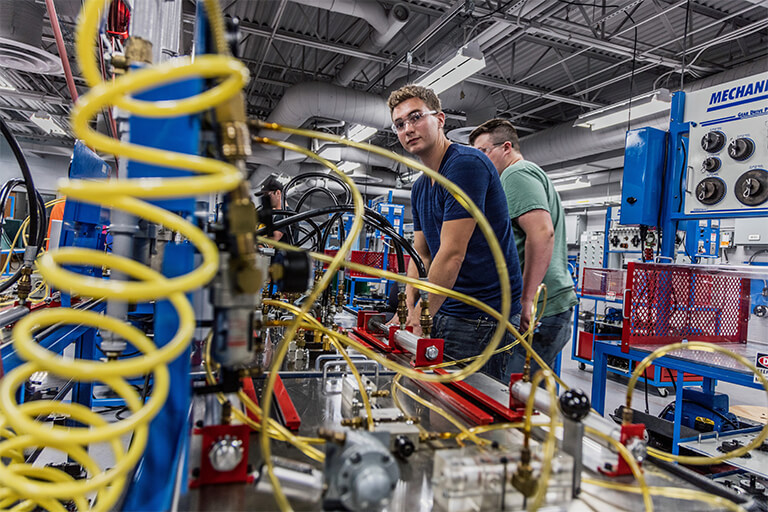 man in workshop smiling at the camera while working on equipment